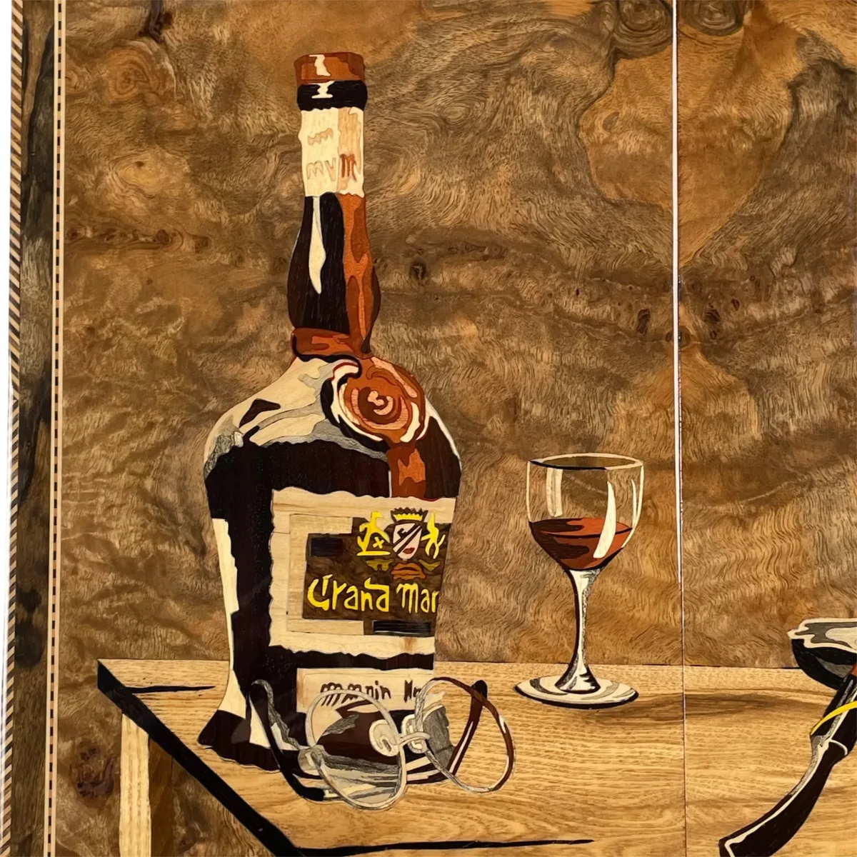 Close-up of the wooden inlay work with bottle, glass and eyeglasses figures on the backgammon lid